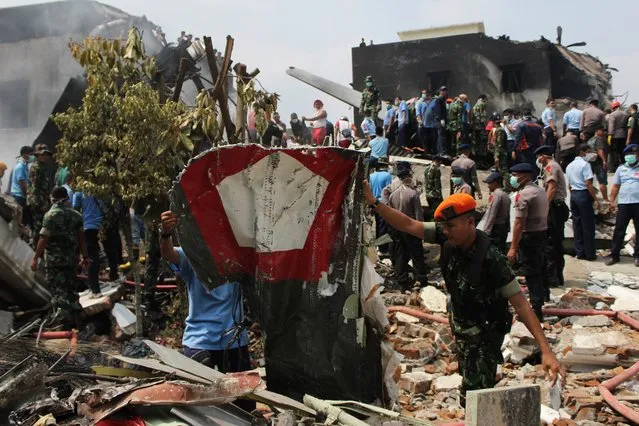 Military personnel retrieve wreckage bearing the Indonesian Air Force roundel from the scene of an Indonesian military C-130 Hercules aircraft crash in Medan on June 30, 2015. (Photo by AFP Photo/ATAR)