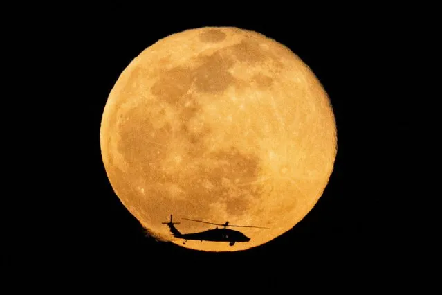 An Israeli army Black Hawk helicopter flies during full moon off the shore of the Mediterranean Sea, near the Israeli border with Gaza, as seen from Ashkelon, Israel on January 18, 2022. (Photo by Amir Cohen/Reuters)