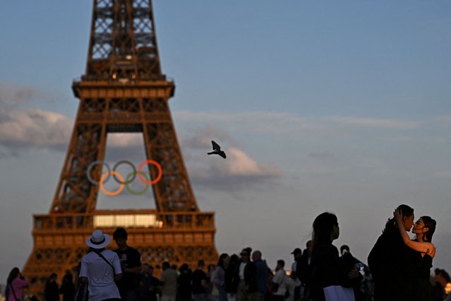 People enjoy the evening as the Olympic rings are displayed on the Eiffel Tower, ahead of the Paris 2024 Olympic games in Paris, France on June 22, 2024. (Photo by Dylan Martinez/Reuters)