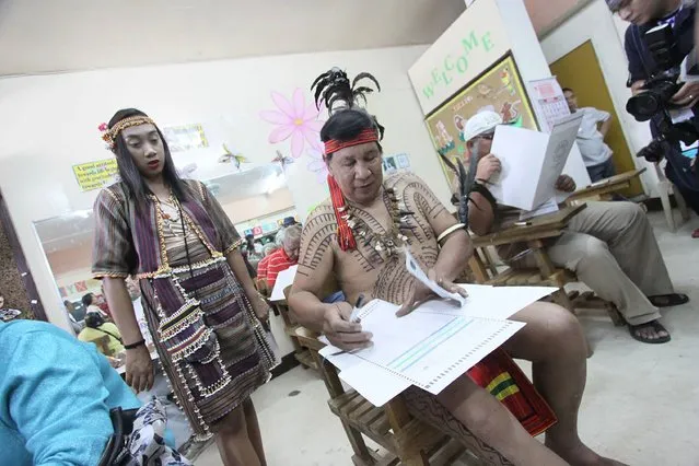 Tribal leader Nicolas Cawed (C), assisted by his daughter Mia Nicole (L), casts his vote in the presidential election at a polling station in Baguio City, north of Manila, on May 9, 2016. Voting was underway in the Philippines on May 9 to elect a new president, with anti-establishment firebrand Rodrigo Duterte the shock favourite after an incendiary campaign in which he vowed to butcher criminals. (Photo by J.J. Landingin/AFP Photo)
