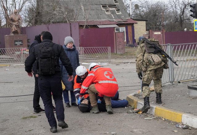 Paramedics administer first aid to an elderly man who fainted after crossing the Irpin river to flee the town of Irpin, close to Kyiv, Ukraine, Monday, March 7, 2022. Irpin residents continue to leave the ruined city under Russian heavy artillery shelling. (Photo by Efrem Lukatsky/AP Photo)