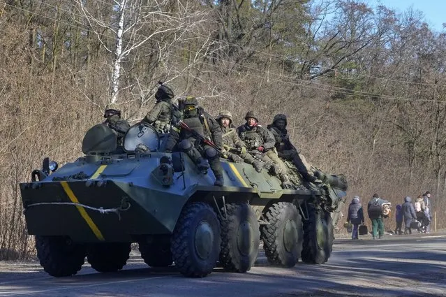 Ukrainian soldiers on an armored personnel carrier pass by people carrying their belongings as they flee the conflict, in the Vyshgorod region close to Kyiv, Ukraine, Thursday, March 10, 2022. (Photo by Efrem Lukatsky/AP Photo)