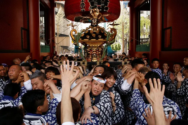People carry a portable shrine, a Mikoshi, through the gate of the Senso-ji Temple during the Sanja festival in Tokyo's Asakusa district, Japan, May 15, 2016. (Photo by Thomas Peter/Reuters)