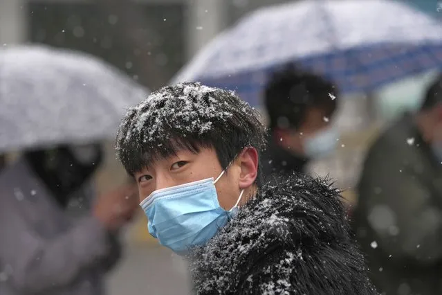 A man lines up for COVID-19 test as it snows on Thursday, March 17, 2022, in Beijing. A fast-spreading variant known as “stealth omicron” is testing China's zero-tolerance strategy, which had kept the virus at bay since the deadly initial outbreak in the city of Wuhan in early 2020. (Photo by Ng Han Guan/AP Photo)