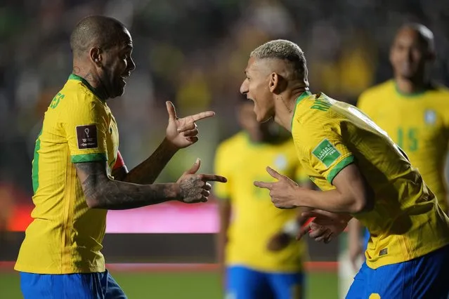 Brazil's Richarlison, right, celebrates with teammate Dani Alves after scoring his side's fourth goal against Bolivia during a qualifying soccer match for the FIFA World Cup Qatar 2022 in La Paz, Bolivia, Tuesday, March 29, 2022. (Photo by Juan Karita/AP Photo)