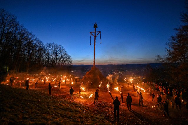 People light the Easter fire with burning torches on a hill in Attendorn, western Germany on April 9, 2023. Easter fires are traditionally lit all over Germany on Easter Saturday and Sunday. In Attendorn, Easter fires with huge crosses are burned on four hills. In addition, burning torches are waved, with which fire circles are painted in the air. (Photo by Ina Fassbender/AFP Photo)