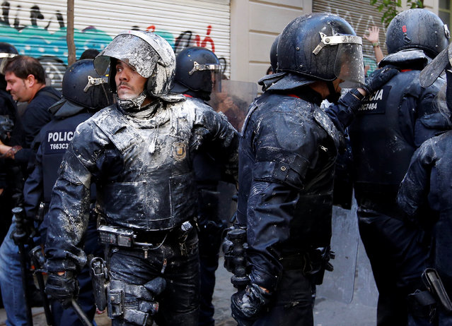 Catalan regional police in full riot gear are covered in flour which was thrown by protesters during a protest over the eviction of squatters earlier in the week from “The Expropriated Bank”, in Barcelona, Spain, May 29, 2016. (Photo by Albert Gea/Reuters)