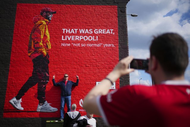 A fan poses for photos next to a mural with the image of Liverpool's manager Jurgen Klopp prior to the English Premier League soccer match between Liverpool and Tottenham Hotspur at Anfield Stadium in Liverpool, England, Sunday, May 5, 2024. (Photo by Jon Super/AP Photo)