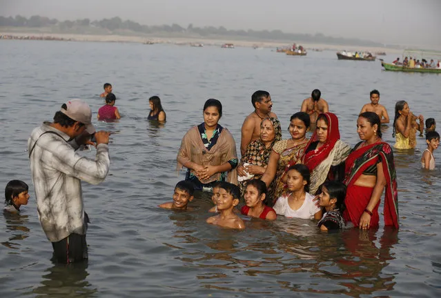 An Indian Hindu family pose for a photograph as they stand in the water at Sangam, the confluence of the Rivers Ganges, Yamuna and mythical Saraswati on Ganga Dussehra, in Allahabad, India, Sunday, June 04, 2017. Hindus across the country are celebrating Ganga Dussehra, devoted to the worship of the River Ganges. (Photo by Rajesh Kumar Singh/AP Photo)