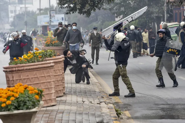 A policeman prepares to beat a lawyer (C) following a clash between lawyers and doctors in Lahore on December 11, 2019. At least three heart patients died on December 11 after a group of lawyers attacked doctors at a cardiac hospital in Pakistan's eastern city of Lahore, officials and ministers said. (Photo by Arif Ali/AFP Photo)