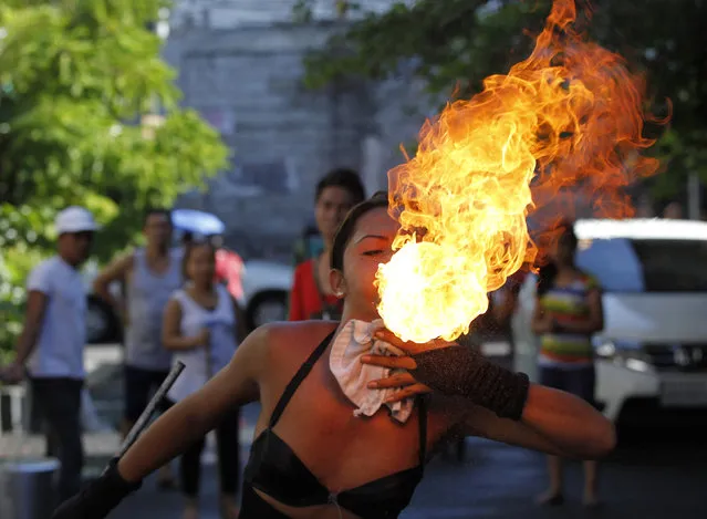 A street performer breathes fire on the eve of the feast day of the town's patron Saint Rita in Paranaque city, metro Manila, May 17, 2014. The annual feast day of Saint Rita is celebrated with colorful street dances and games on the third Sunday of May. (Photo by Romeo Ranoco/Reuters)