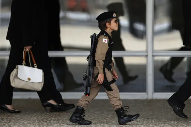 A boy dressed in a military police costume arrives to watch the Changing of the Guard at the Planalto Presidential Palace, in Brasilia, Brazil, Thursday, November 28, 2019. (Photo by Eraldo Peres/AP Photo)