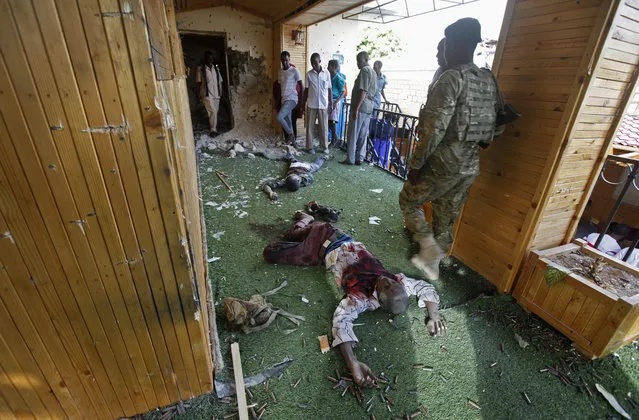 Somali soldiers and others stand near the bodies of some of the al-Shabab attackers at the scene of a car bomb blast and gun battle targeting a restaurant in Mogadishu, Somalia Thursday, June 15, 2017. Somalia's security forces early Thursday morning ended a night-long siege by al-Shabab Islamic extremists at the popular “Pizza House” restaurant in the capital. (Photo by Farah Abdi Warsameh/AP Photo)