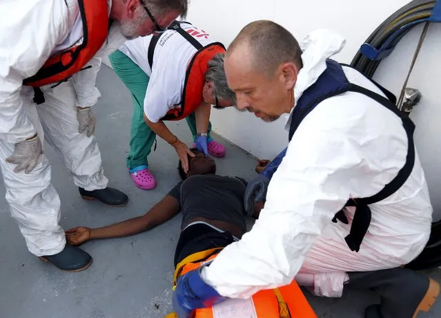 Medecins san Frontiere (MSF) medics examine a semi-conscious migrant who was brought onto the Migrant Offshore Aid Station (MOAS) ship MV Phoenix, some 20 miles (32 kilometres) off the coast of Libya, August 3, 2015. (Photo by Darrin Zammit Lupi/Reuters)