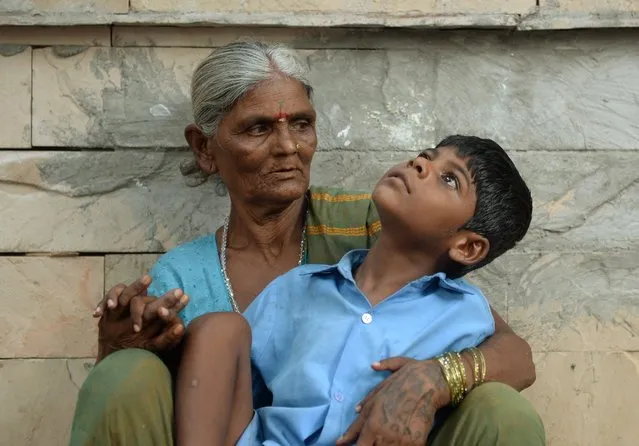 In this photograph taken on May 20, 2014 nine year old Indian boy Lakhan Kale sits with his grandmother on the pavement in Mumbai. (Photo by Punit Paranjpe/AFP Photo)