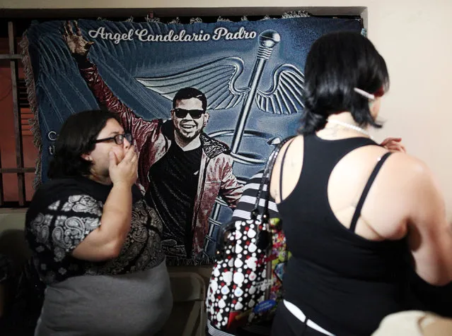 Family and friends mourn at the wake for Angel Candelario, one of the victims of the shooting at the Pulse night club in Orlando, as a tapestry with his image hangs on a wall in his hometown of Guanica, Puerto Rico, June 16, 2016. (Photo by Alvin Baez/Reuters)
