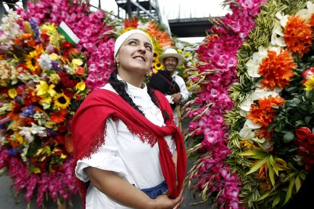 A flower grower, known as a silletero, looks at flower arrangements as she participates in the annual flower parade in Medellin, Colombia, August 9, 2015. (Photo by Fredy Builes/Reuters)