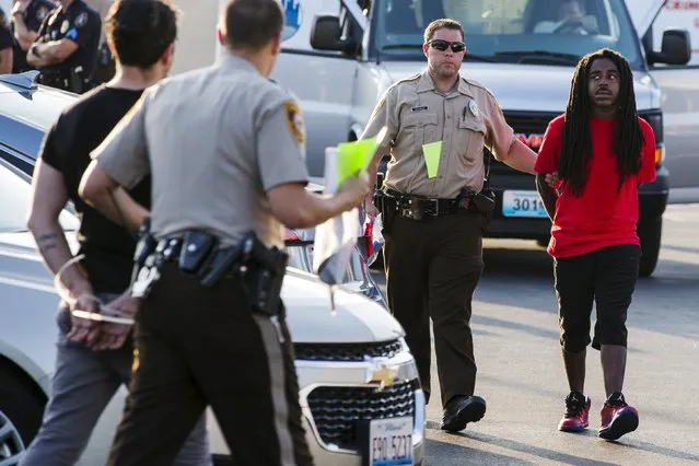 Officers from the St Louis County Police Department process demonstrators from the “Black Lives Matter” movement who had been arrested for protesting on Interstate 70 in Earth City, Missouri, August 10, 2015. Dozens of protesters were arrested on Monday afternoon after blocking rush-hour traffic on Interstate 70 a few miles (km) from Ferguson, Missouri, during demonstrations over the police shooting of an unarmed black man a year ago, according to a Reuters witness. (Photo by Lucas Jackson/Reuters)