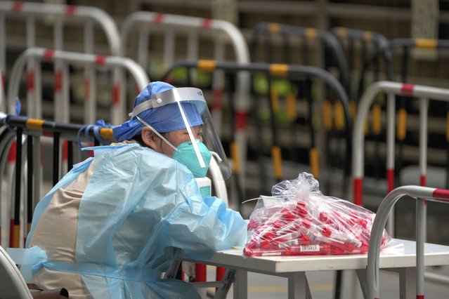 A volunteer in protective gear waits for residents at a coronavirus testing facility in Beijing, Thursday, June 9, 2022. (Photo by Andy Wong/AP Photo)