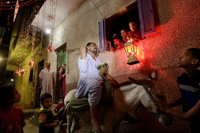 In this Friday, July 10, 2015 photo, a girl hold a traditional lantern as Essam Sayed, the 45-year-old "mesaharati," or dawn caller, bangs his drum and chants to wake people up for a meal before sunrise, during the Islamic holy month of Ramadan, in the Arab Ghoneim district of Helwan on the southern outskirts of Cairo, Egypt. (AP Photo/Amr Nabil)