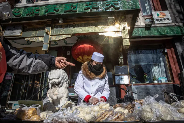 A seller wearing a protective face mask packs food for customers on the street near the Houhai lake, in Beijing, China, 17 February 2020. The disease caused by the novel coronavirus (SARS-CoV-2) has been officially named Covid-19 by the World Health Organization (WHO). The outbreak, which originated in the Chinese city of Wuhan, has so far killed at least 1,776 people and infected over 71,000 others worldwide, mostly in China. (Photo by Roman Pilipey/EPA/EFE)