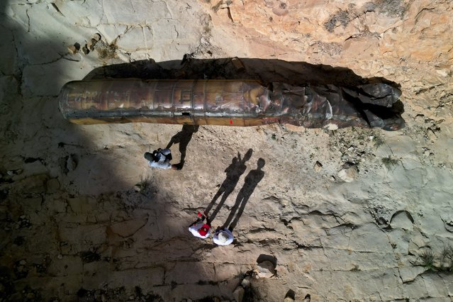 A drone view shows members of military personnel in civilian clothing inspecting apparent remains of a ballistic missile lying in the desert, following a massive missile and drone attack by Iran on Israel, near the southern city of Arad, Israel on April 24, 2024. (Photo by Amir Cohen/Reuters)