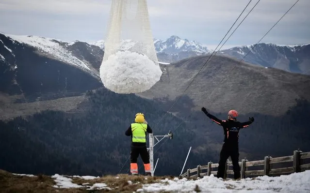 People look at an helicopter carrying snow in order to place it on a ski slope in the Superbagneres station, near Luchon, in French Pyrenees mountain southwestern France, on February 15, 2020. The French department of Haute-Garonne decided to pour snow by helicopter on the Luchon-Superbagneres station in order to make up for the lack of snow on February 14 and February 15, 2020. (Photo by Anne-Christine Poujoulat/AFP Photo)