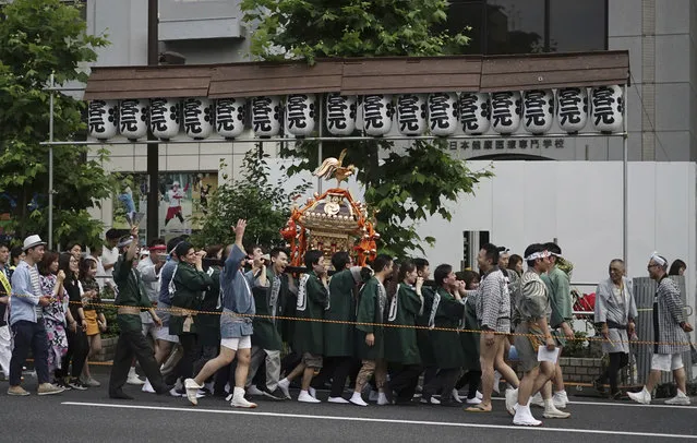 Residents and foreigners from a local neighborhood carry a portable shrine to celebrate the annual festival of Torigoe Shrine Saturday, June 10, 2017, in Tokyo. (Photo by Eugene Hoshiko/AP Photo)