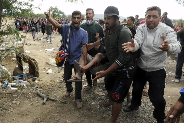 Migrants carry their injured fellow during clashes with Macedonian police at the Greek-Macedonian border, August 21, 2015. (Photo by Alexandros Avramidis/Reuters)