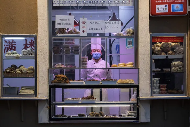 In this photo taken Saturday, February 22, 2020, a chef looks out from behind a display of food products at a restaurant in Beijing, China. (Photo by Ng Han Guan/AP Photo)