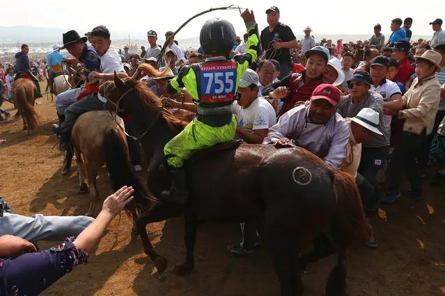 Mongolian people gather to try to touch a horse for good luck in the finishing area of the “Soyolon” (Five-year-old horse) horse racing competition during Naadam Festival in Ulan Bator, the capital of Mongolia, 12 July 2016. The annual Naadam Festival is the largest traditional festival throughout Mongolia during the midsummer. The festival is also known as the “three games of men” including three traditional Mongolian pageants - horse racing, wrestling and archery. (Photo by Wu Hong/EPA)