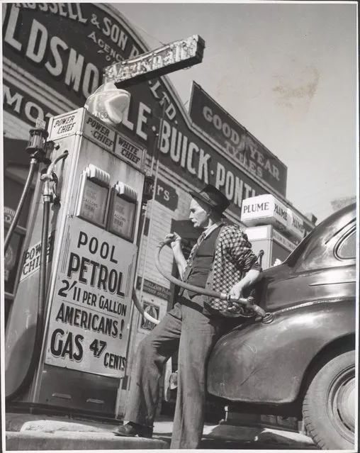 William Russell putting the four gallon monthly ration of petrol into a customer's car, Drouin, Victoria, ca. 1944. Home town Australia. Drouin's biggest service station (there are two) is owned by a company consisting of 80 year old William D. Russell and his family. Mr Russell is putting the four gallon monthly ration of gas onto a customers car