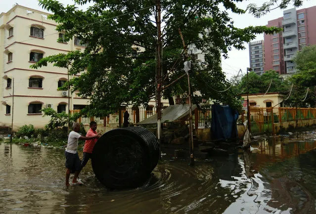 Men push a water tank through a partially flooded street at a residential area in Mumbai, August 30, 2017. (Photo by Danish Siddiqui/Reuters)