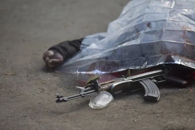 The body of prison guard Juan Sical Toj lies covered in a plastic sheet next to his weapon outside the Roosevelt Hospital after an assault staged by unknown attackers, in Guatemala City, Wednesday, August 16, 2017.  Gunmen stormed the Roosevelt, one of Guatemala's largest hospitals, and opened fire early Wednesday in an assault staged to free an imprisoned gang member, officials said. At least seven people were killed and five were arrested. (Photo by Luis Soto/AP Photo)