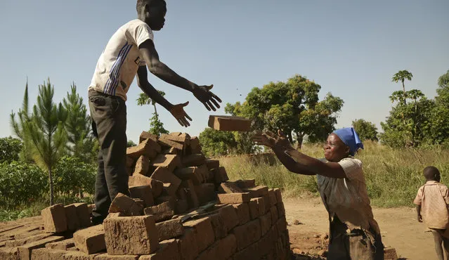 In this photo taken Wednesday, December 13, 2017, Jackline Akot, 36, who was abducted by the Lord's Resistance Army (LRA) as a teenager and had two children before escaping, stacks the bricks that she and her family make in Laliya Oguru village, near Gulu, in Uganda. (Photo by Adelle Kalakouti/AP Photo)