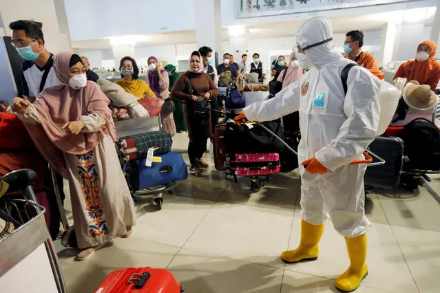 A traveler reacts as a worker sprays disinfectant on passengers' baggages at the international arrivals terminal of Soekarno-Hatta Airport near Jakarta, amid the coronavirus disease (COVID-19) outbreak, Indonesia, March 13, 2020. (Photo by Willy Kurniawan/Reuters)