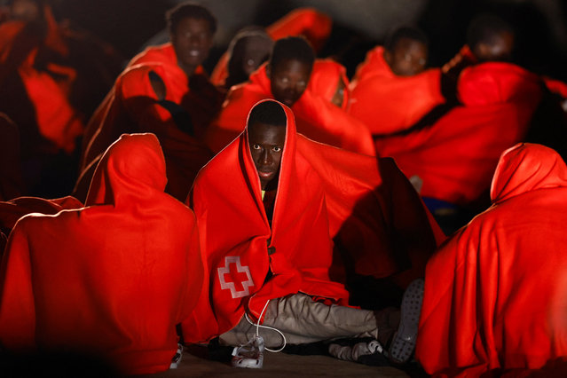 A group of migrants waits to be treated by the Red Cross after arriving on a fibreglass boat, at the beach of Castillo del Romeral on the island of Gran Canaria, Spain on December 29, 2024. (Photo by Borja Suarez/Reuters)