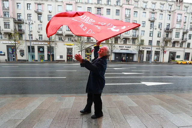 A woman waves a Victory Banner in Tverskaya Street on the day of the 75th anniversary of the victory over Nazi Germany in World War II on May 9, 2020. Moscow Mayor Sobyanin has extended the self-isolation regime in Moscow till May 31, 2020 to prevent the spread of the novel coronavirus. (Photo by Sergei Fadeichev/TASS via Getty Images)