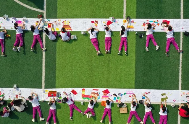 This aerial photo taken on September 28, 2022 shows elementary school students colouring pictures ahead of the upcoming National Day in Handan in China's northern Hebei province. (Photo by AFP Photo/China Stringer Network)