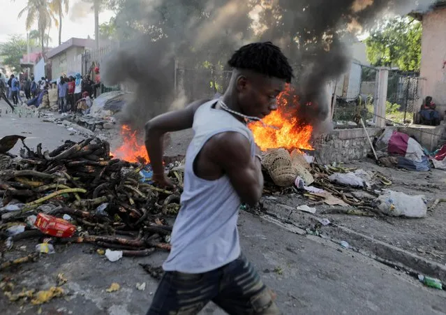 A man runs past a burning street barricade during a protest against the government and rising fuel prices, in Port-au-Prince, Haiti on October 3, 2022. (Photo by Ralph Tedy Erol/Reuters)