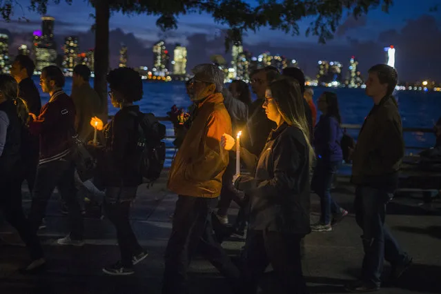 People walk carrying lit candles along Hudson River during a vigil and memorial march near the crime scene to remember the victims of the recent truck attack on Thursday, November 2, 2017, in New York. A man in a rental truck mowed down pedestrians and cyclists along the busy bike path near the World Trade Center memorial on Tuesday, killing at least eight people and seriously injuring others in what the mayor called “a particularly cowardly act of terror”. (Photo by Andres Kudacki/AP Photo)