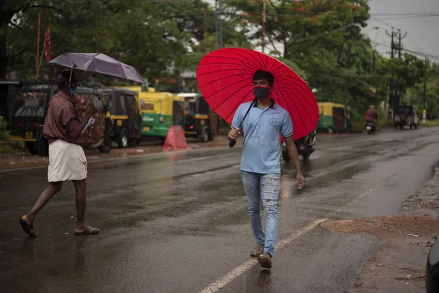 People wearing masks as precaution against the coronavirus walk holding umbrellas during monsoon rains in Kochi, Kerala state, India, Saturday, June 6, 2020. India which surpasses Italy as the sixth worst-hit by the coronavirus caseload is trying to contain the chain of transmission while allowing social and economic activity to resume. (Photo by R.S. Iyer/AP Photo)
