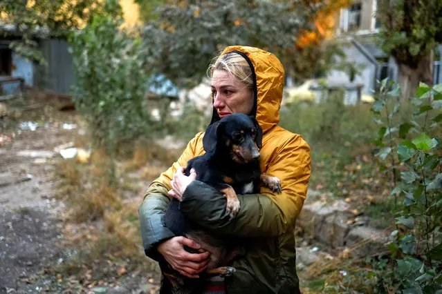 A woman carries a dog at a site of a residential building heavily damaged by a Russian missile strike, amid their attack on the country, in Mykolaiv, Ukraine on October 18, 2022. (Photo by Valentyn Ogirenko/Reuters)