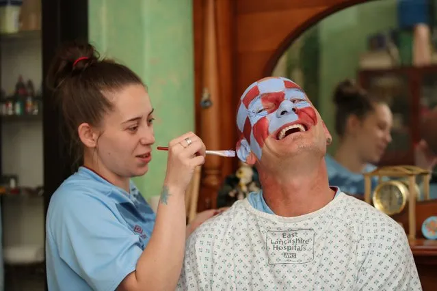 John Withington has his face painted by his daughter in his home before the Manchester City v Burnley match, as play resumes behind closed doors, in Burnley, England, on June 22, 2020. (Photo by Molly Darlington/Action Images via Reuters)