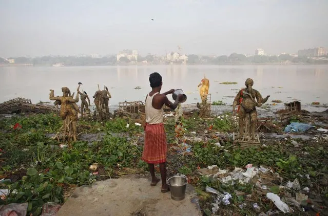 A man pours water on the polluted banks of river Ganges beside the idols of Hindu god and goddess that were immersed during the Durga Puja festival in Kolkata October 20, 2010. (Photo by Reinhard Krause/Reuters)