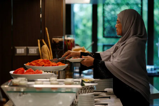 A Muslim visitor takes food from a platter for her breakfast at the Al Meroz hotel in Bangkok, Thailand, August 29, 2016. (Photo by Chaiwat Subprasom/Reuters)