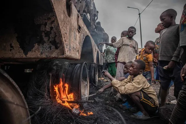 Children dismantle a vehicle belonging to the United Nations Organization Stabilization Mission in the Democratic Republic of the Congo (MONUSCO) in Kanyaruchinya, part of Nyiragongo territory in the Democratic Republic of Congo, on November 2, 2022, after it was set on fire overnight by angry residents. (Photo by Aubin Mukoni/AFP Photo)