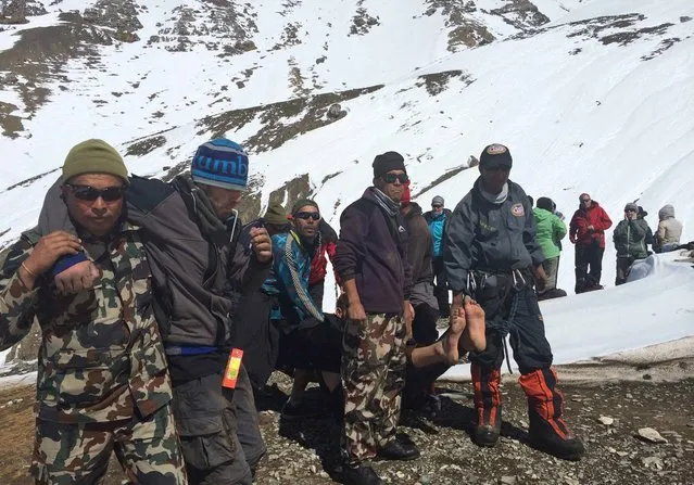 In this handout photo provided by the Nepalese army, rescue team members carry avalanche victims to safety at Thorong La pass area in Nepal, Friday, October 17, 2014. Rescuers widened their search Friday for trekkers stranded since a series of blizzards and avalanches battered the Himalayas in northern Nepal early this week, leaving at least 29 foreigners and locals dead, officials said. (Photo by AP Photo/Nepalese Army)