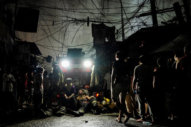 Firefighters take a break next to residents watching the fire at a residential area in Manila, Philippines, on April 23, 2025. (Photo by Lisa Marie David/Reuters)