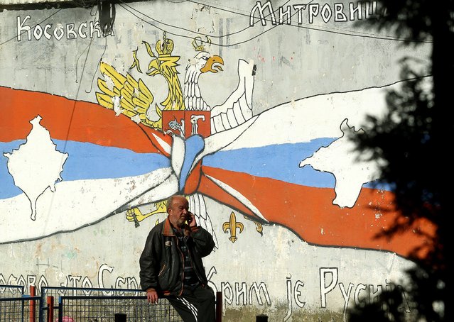 A man talks on the phone in front of a mural that shows Serbian (L) and Russian (R) flags with maps of Kosovo and Crimea in the northern, Serb-dominated part of ethnically divided town of Mitrovica, Kosovo, 01 November 2022. The Government of Kosovo will begin implementing a plan to eliminate the usage of Serbian car license plates. All owners of vehicles with Serbian number plates are warned and requested to visit any of the Vehicle Registration Centers and register their vehicles with RKS license plates. In the Serbian community of Kosovo, the RKS license plates are seen as unacceptable as they suggest the recognition of independence of the Republic of Kosovo. (Photo by Djordje Savic/EPA/EFE)